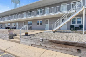 Exterior of a staged 1-bedroom beach condo in Seaside Park NJ with white railings, patios, and a coastal condo courtyard.