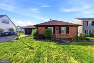 Exterior view of a staged 3-bedroom brick ranch home in Willingboro NJ with a front lawn, driveway, and single-car garage.