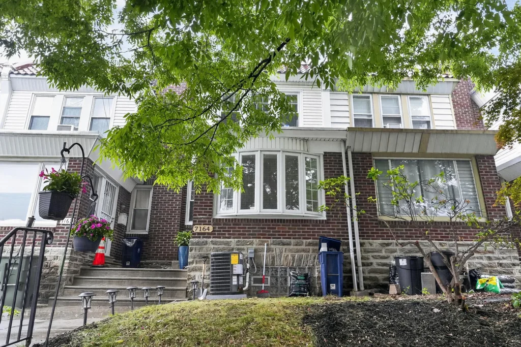Exterior of a staged 4-bedroom brick home in West Oak Lane Philadelphia with a bay window, front steps, and tree-lined residential setting.