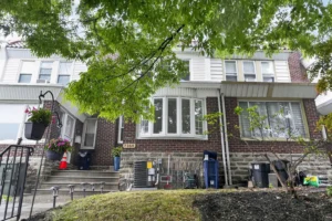 Exterior of a staged 4-bedroom brick home in West Oak Lane Philadelphia with a bay window, front steps, and tree-lined residential setting.